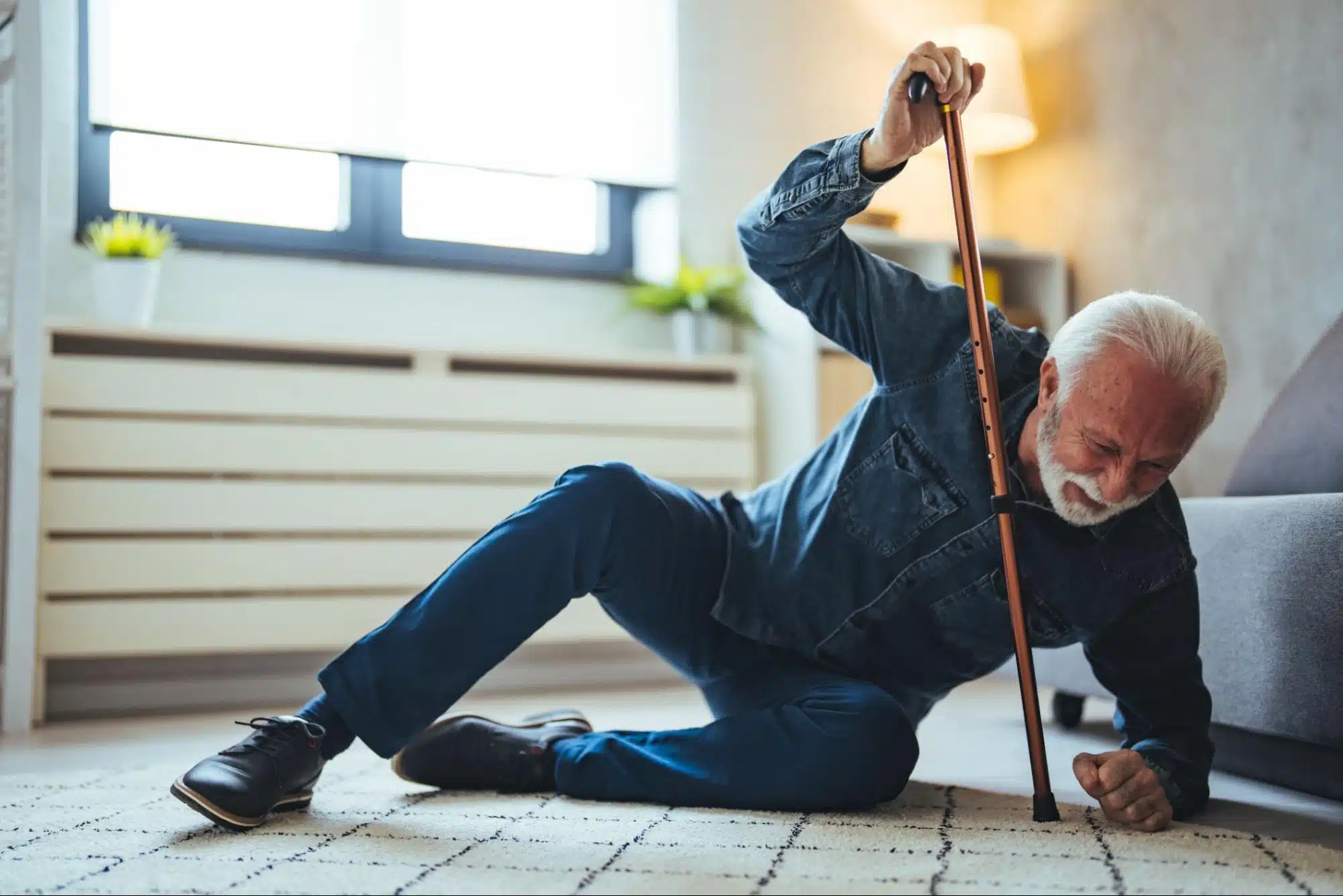 an elderly man using a walking stick to help him up off the ground.