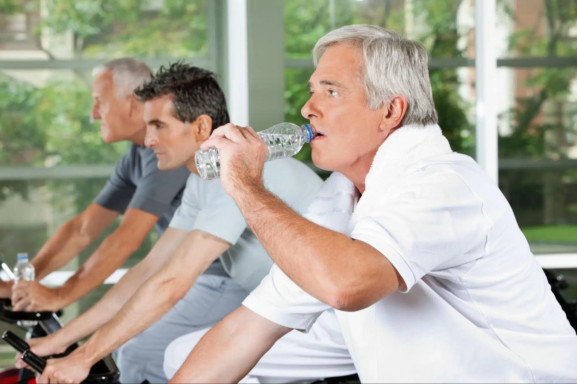 Man drinking water while on an exercise bike