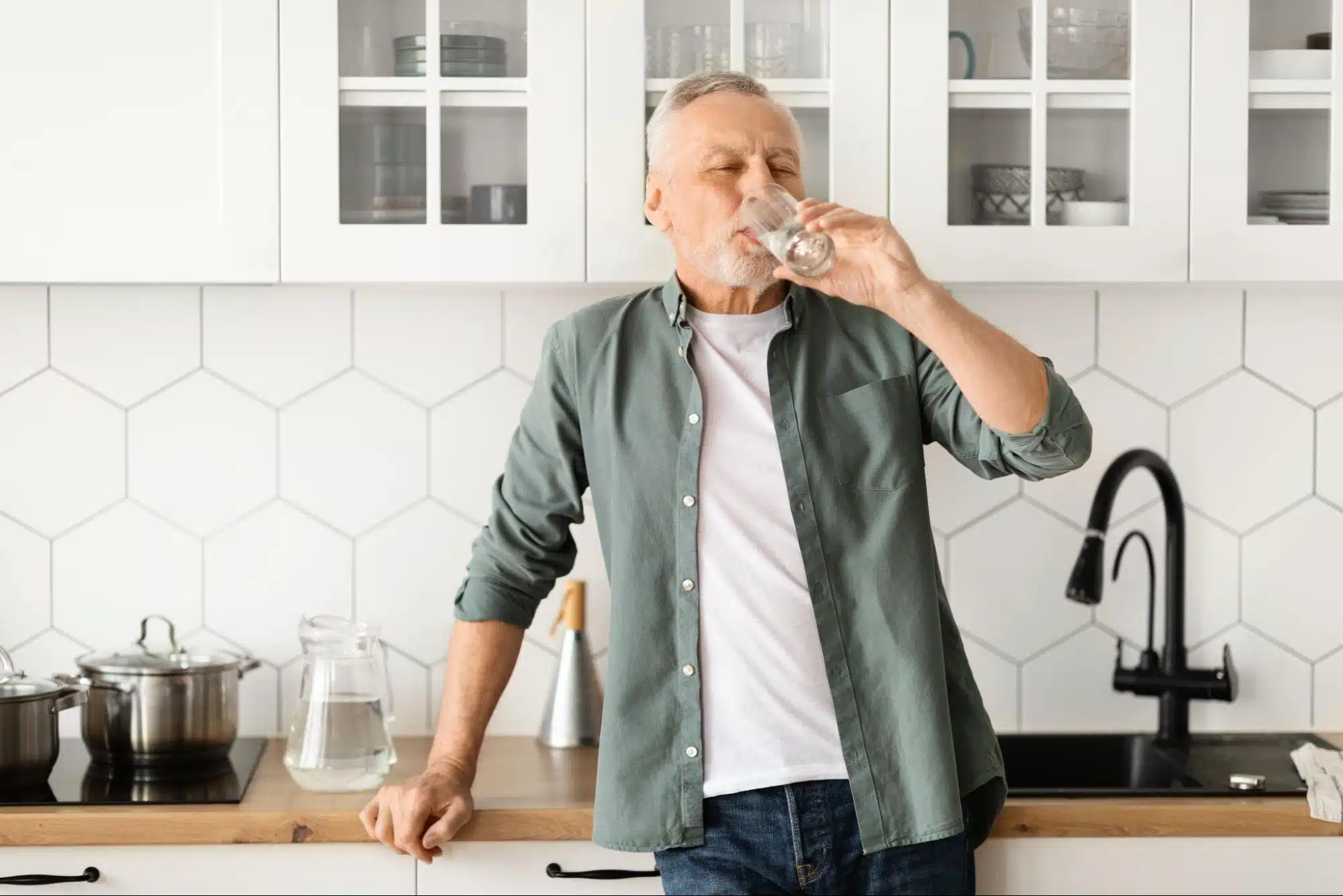 a man drinking water in a kitchen