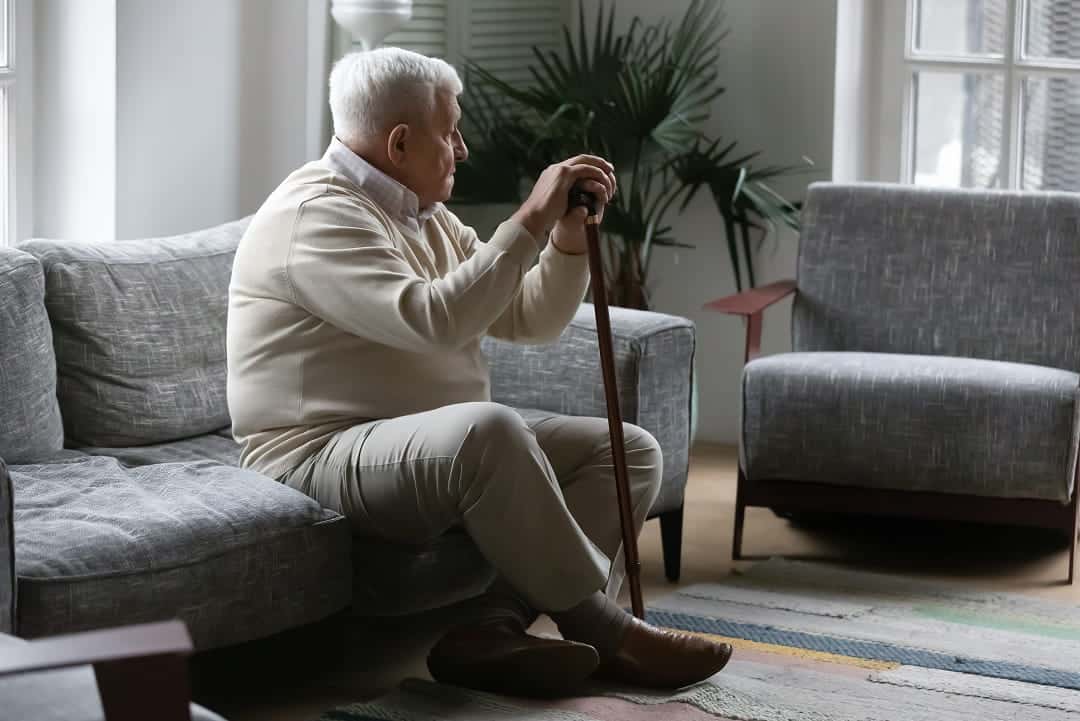 A senior sitting down staring outside a window