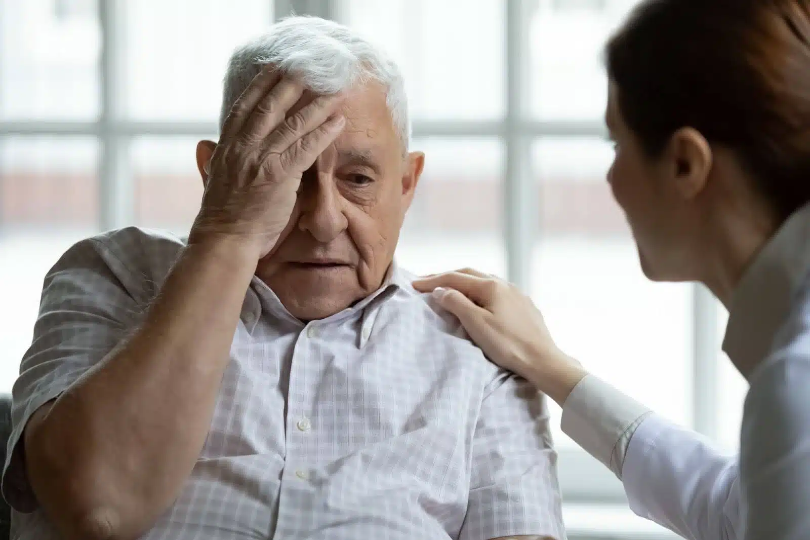 Older person looking stressed and being comforted.