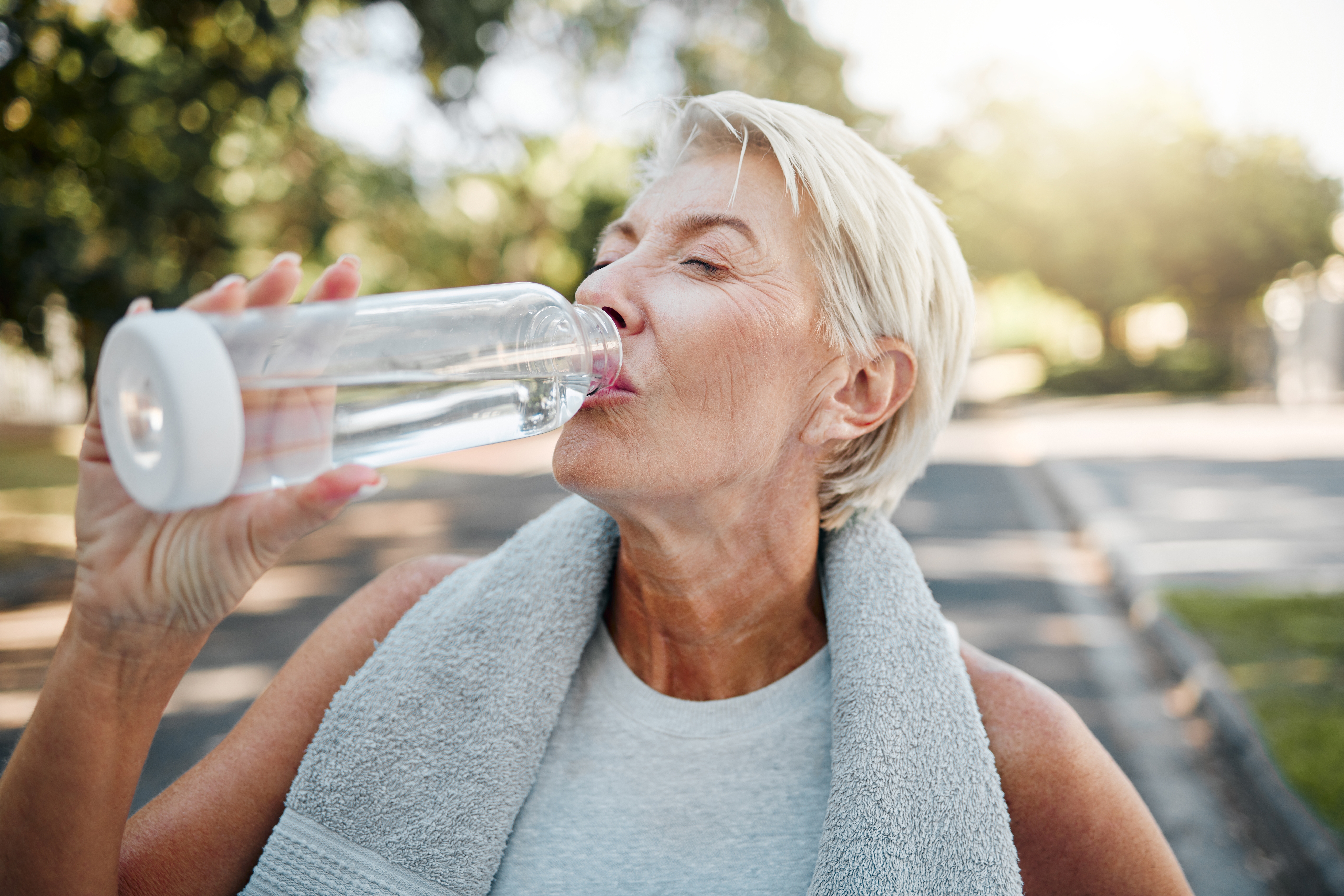 Senior woman drinking a bottle of water outside