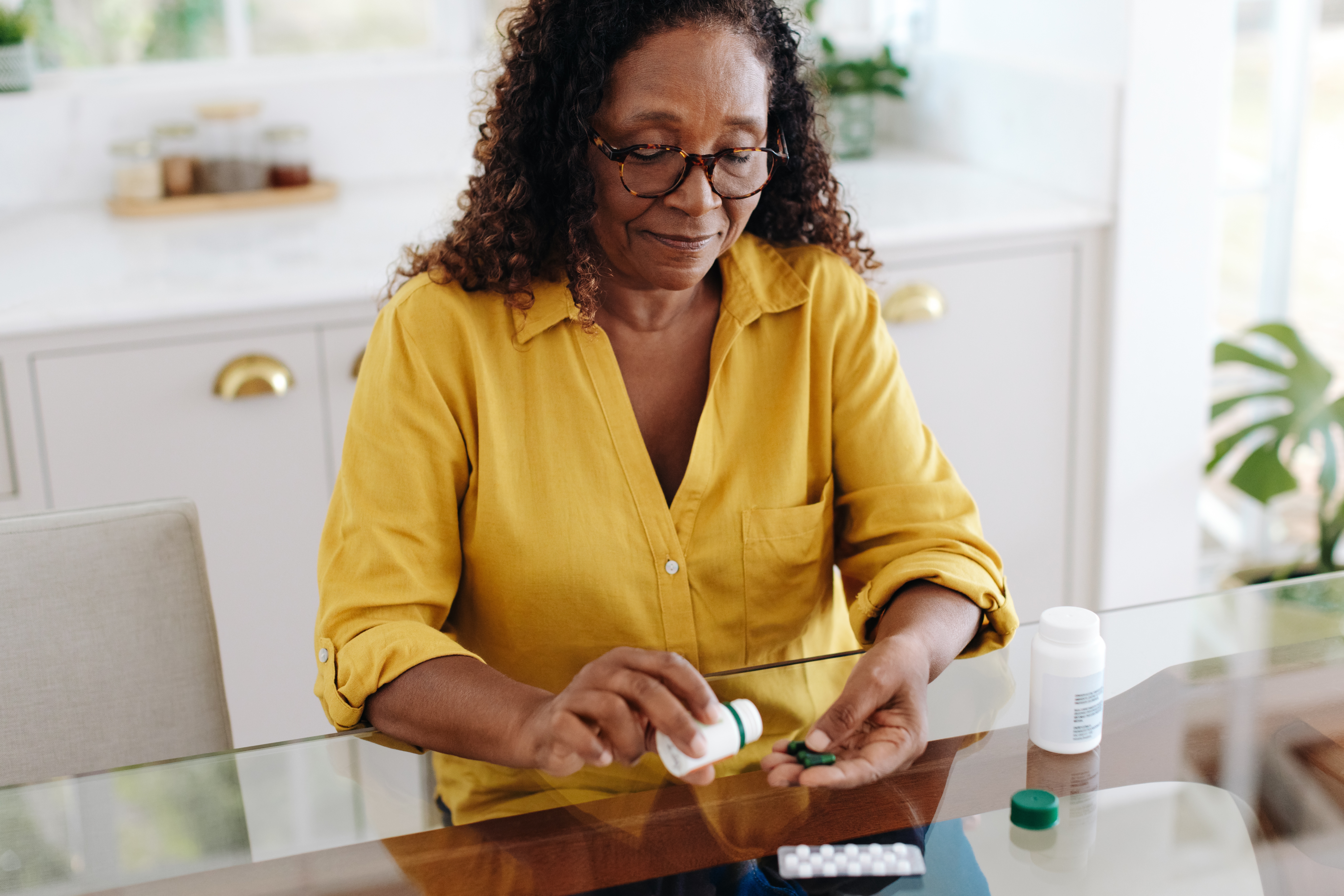 Senior woman reviewing her medications at kitchen table
